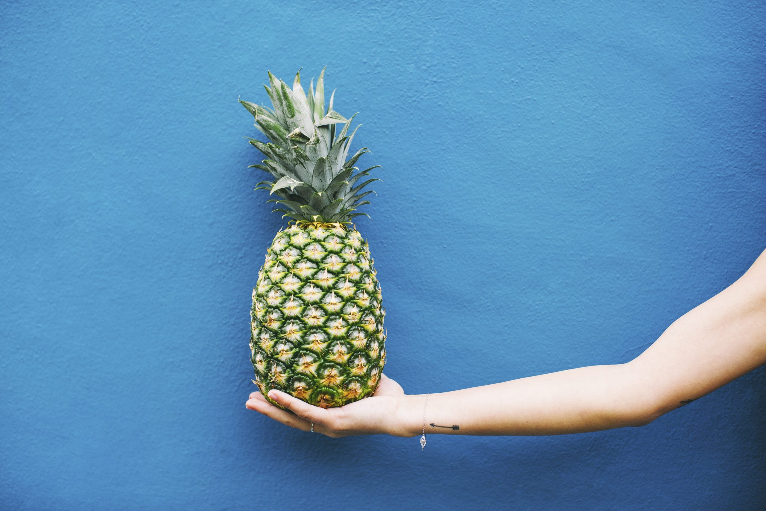woman holding a pineapple, one of several anti-inflammation foods