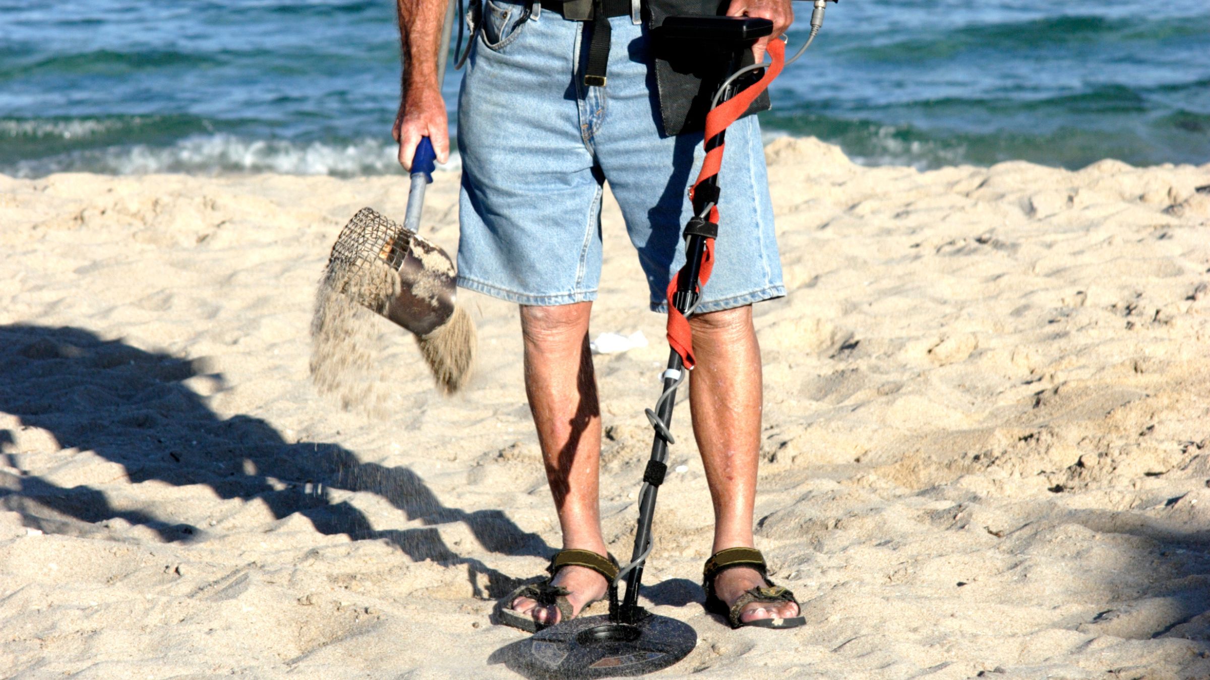 Man in jean shorts beachcombing